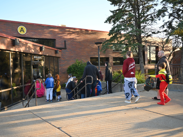 Children and parents dressed up for halloween to walk into a building
