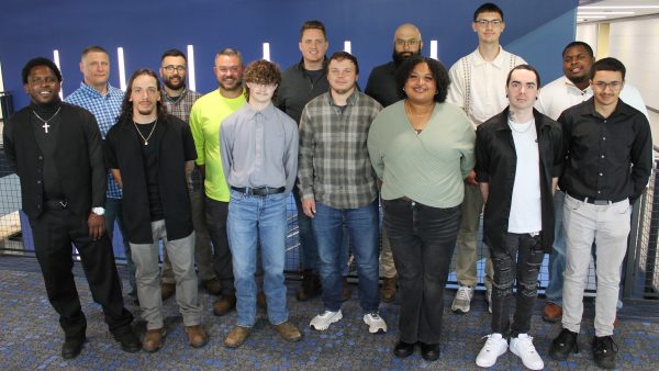 14 people standing and smiling at camera.
