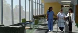 A person in blue scrubs standing in a room with windows