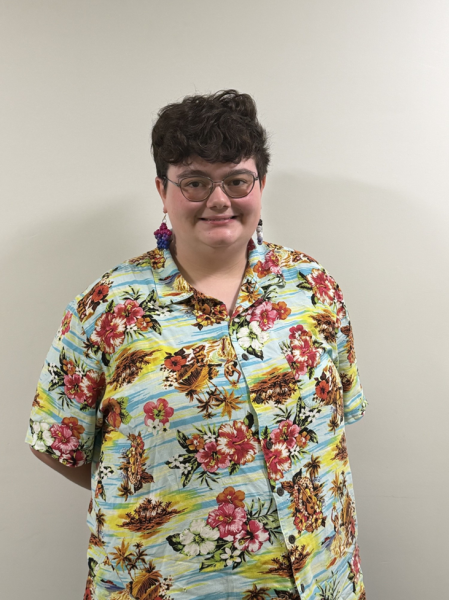 Pride alliance remains a community circle for bhc Photo of jen. They are wearing a colorful button up shirt, glasses and earrings.