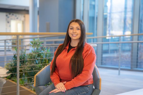 From busy mom to business graduate Smiling woman sitting indoors, casual attire.