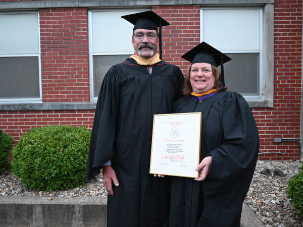 A man and woman in graduation gowns and cap and gowns