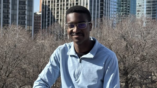 man smiling at camera with trees and Chicago downtown building in background.