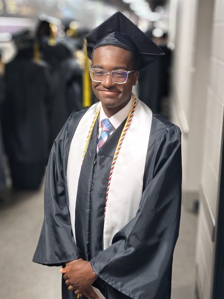 College graduate in cap and gown smiling at camera.