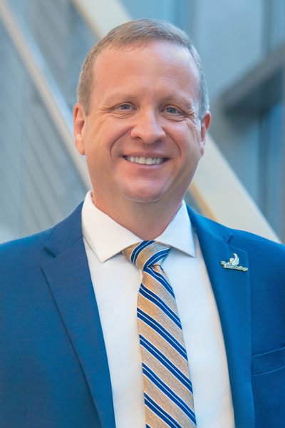Headshot of president jeremy thomas of black hawk college. A smiling man in a blue suit.