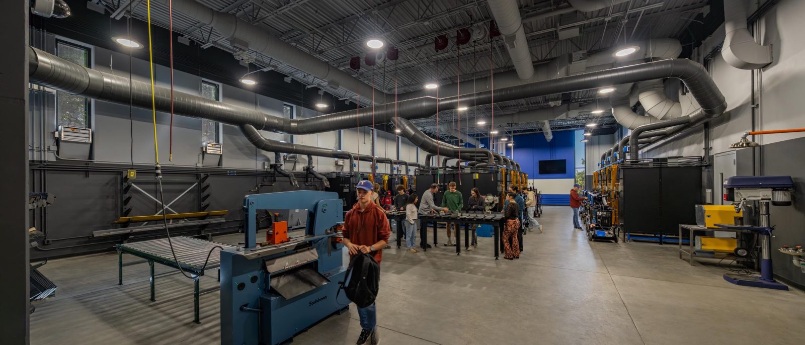 Industrial welding lab with equipment and people.