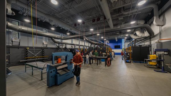 Industrial welding lab with equipment and people.