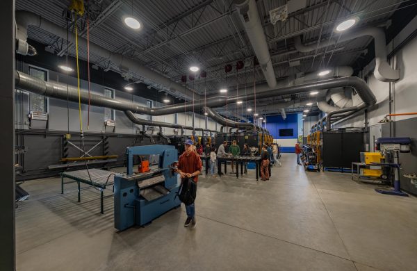 Industrial welding lab with equipment and people.