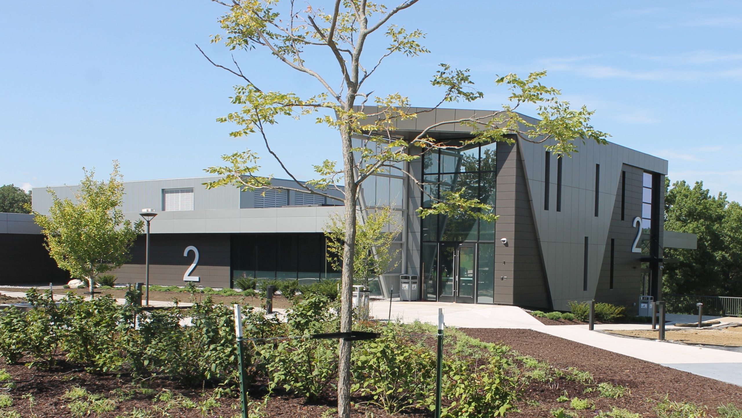 exterior of two-story academic building with landscaping and sidewalks