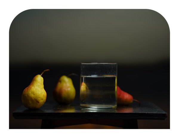Artistic photograph of 3 pears and clear glass of water.