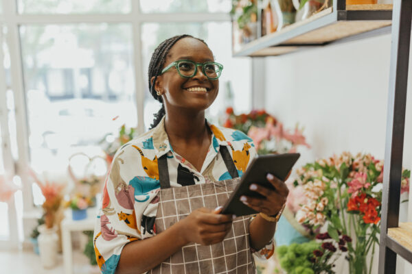 A black woman holding a tablet in a floral shop.