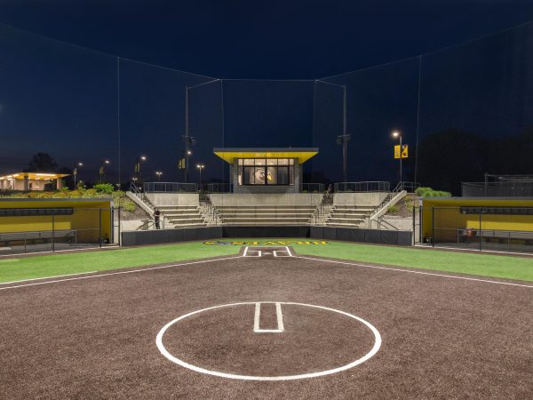 A softball field with a stadium and a building