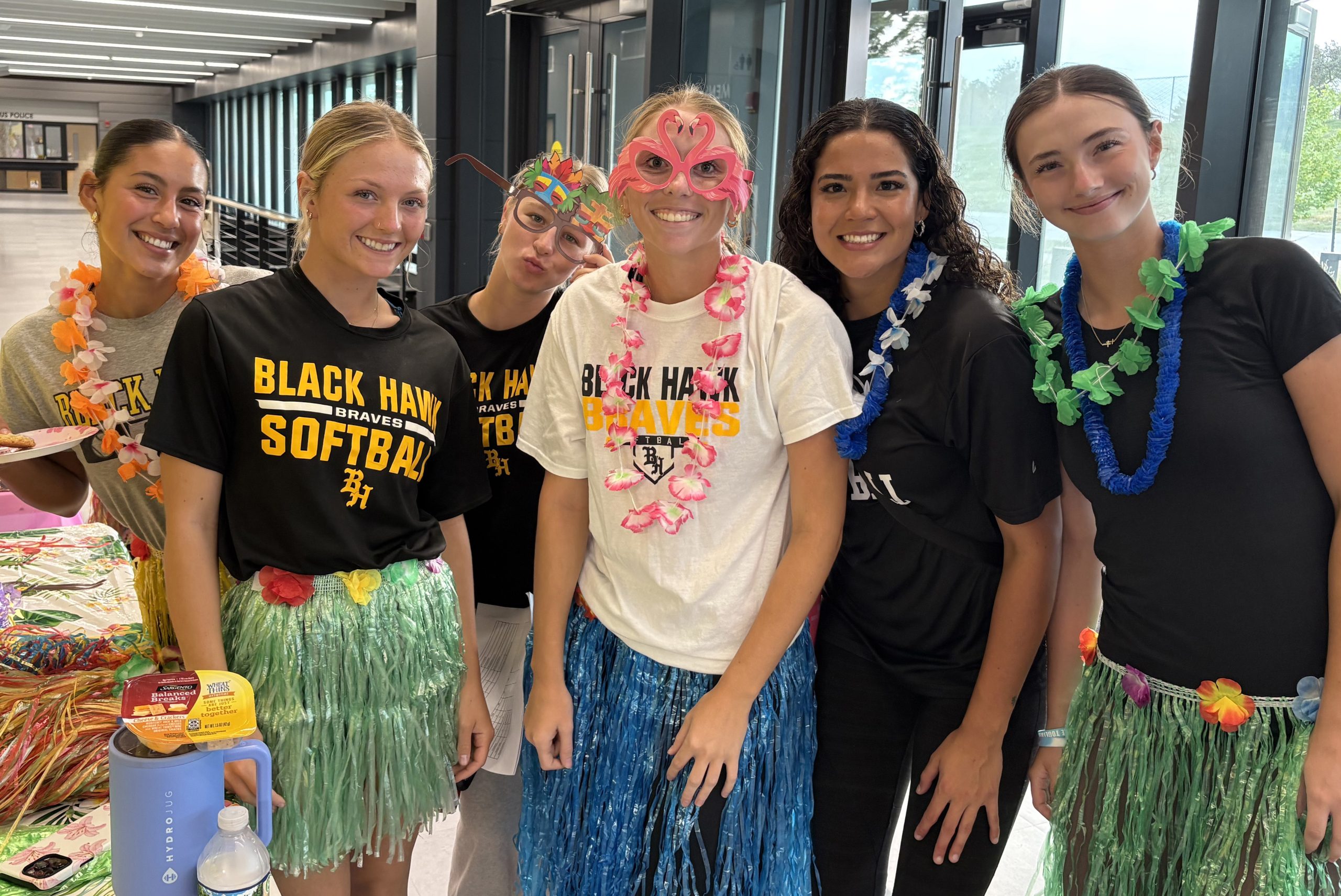 6 women's softball players wearing T-shirts, leis and grass skirts.