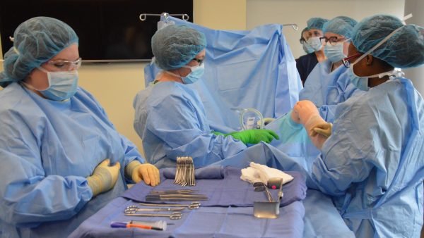 Surgical tech students at operating tables with instruments.