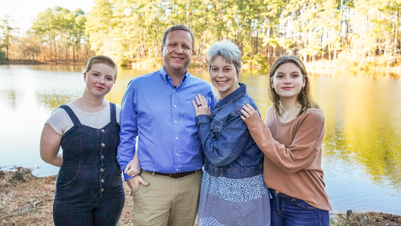President jeremy thomas and family pose in front of a lake.