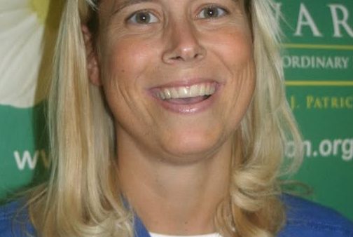 head and shoulders shot of smiling woman wearing medical scrubs shirt.