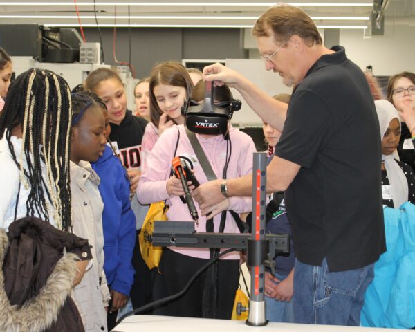 Junior high school girl trying virtual welding with other students watching