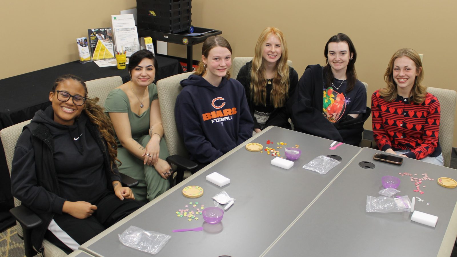 6 women sitting at a table and smiling at the camera.
