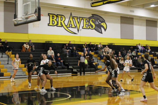 A women's basketball game in a gymnasium with players from the