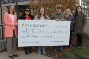 6 people standing outdoors holding oversized check