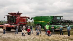 People in masks in front of farming equipment