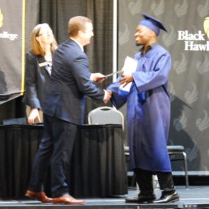 Bhc president dr. Jeremy thomas handing certificate to ged grad tony johnson on stage