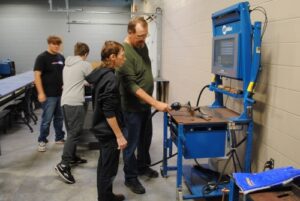 College instructor paul ericson showing high school student how to use welding simulator