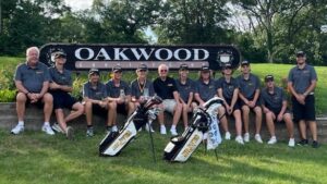 Golfers and coaches sitting in front of oakwood country club sign