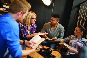 4 people looking at books and talking