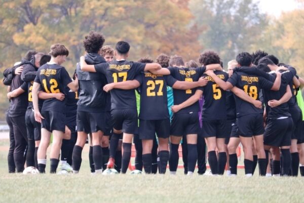Men's soccer mte Soccer players huddling on field with arms around each other