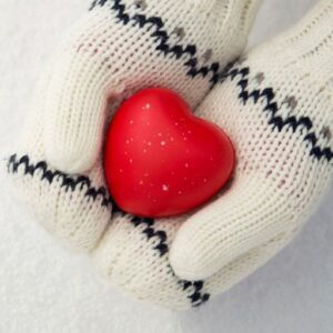 Hands in white mittens holding red heart