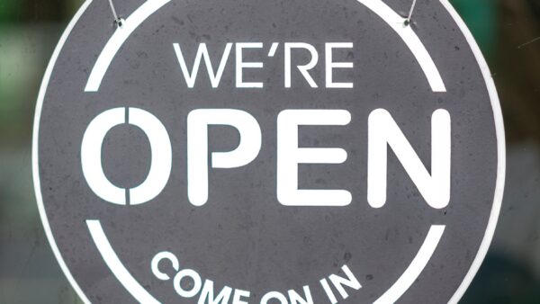 circular sign that says we're open come on in.