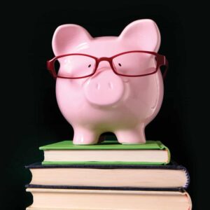 Pink piggy bank wearing red glasses on stack of books