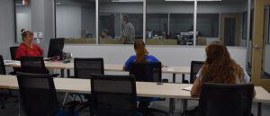 People sitting at tables in a room, testing for current students