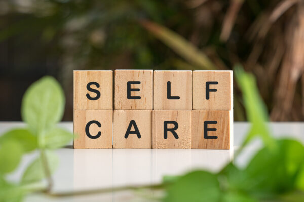 Self care word on wooden blocks surrounded by green nature