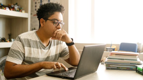 Student studying on laptop at a table at home.