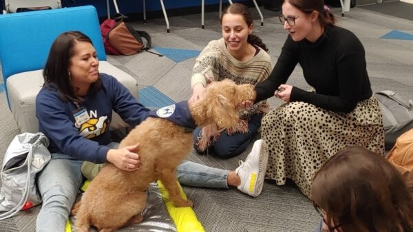 First generation and underrepresented students 2 smiling students petting dog